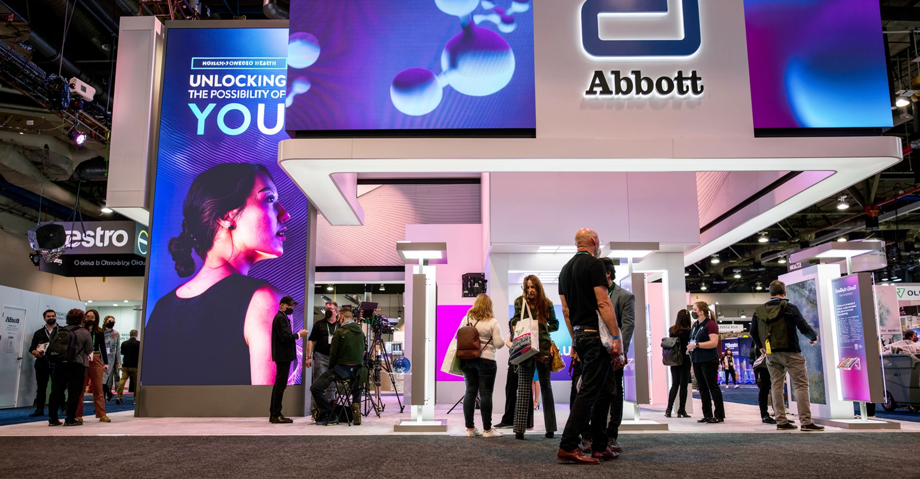Visitors at the Abbott booth beneath the screens